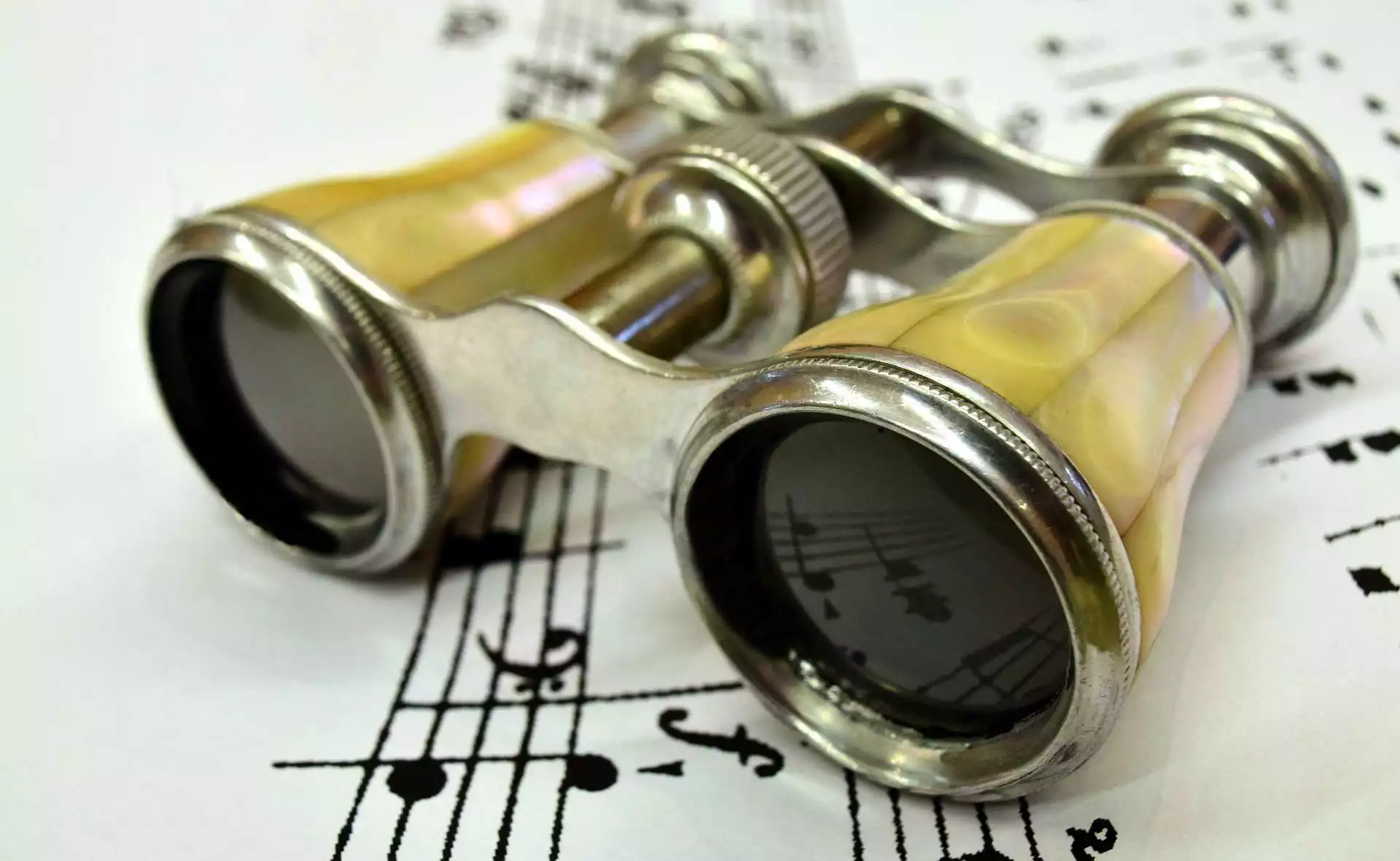 Theatre binoculars on a music score, symbolising the Mhodì vision of looking far and deep
