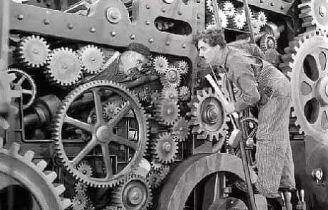 Charlie Chaplin among the gears of Modern Times, a metaphor for the industrial monotony that crushes creativity